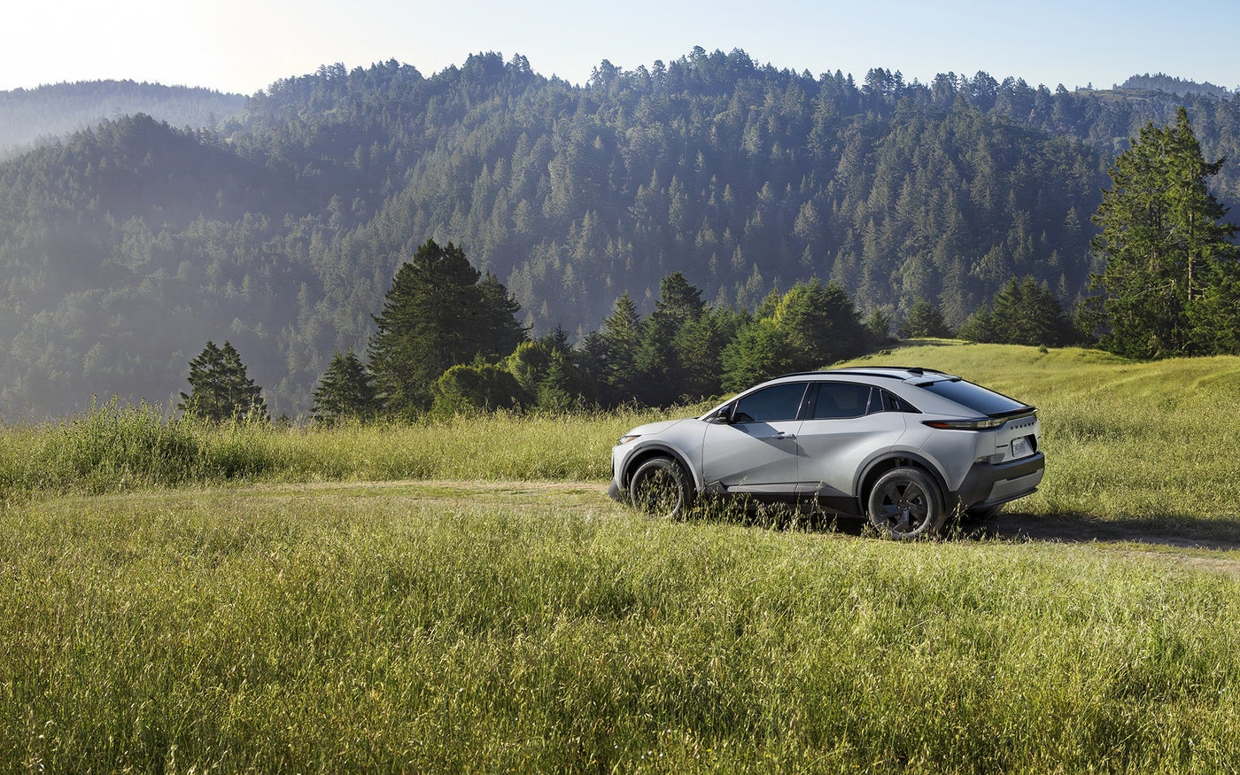 A Subaru Uncharted SUV is parked on a grassy hill in the mountains.