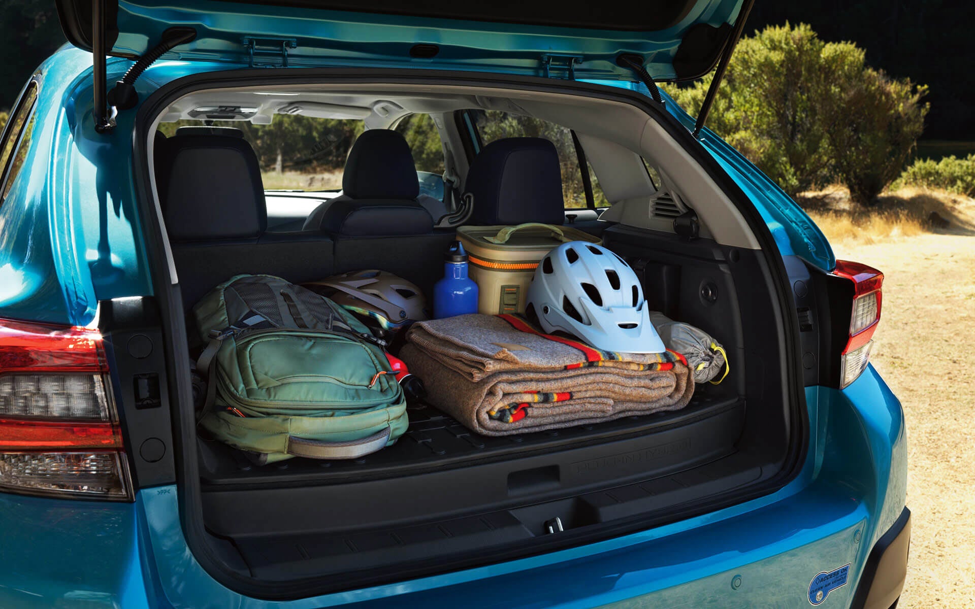 A backpack, blanket, and bike helmet in the rear cargo area of a Crosstrek Hybrid | Subaru of Ann Arbor in Ann Arbor MI